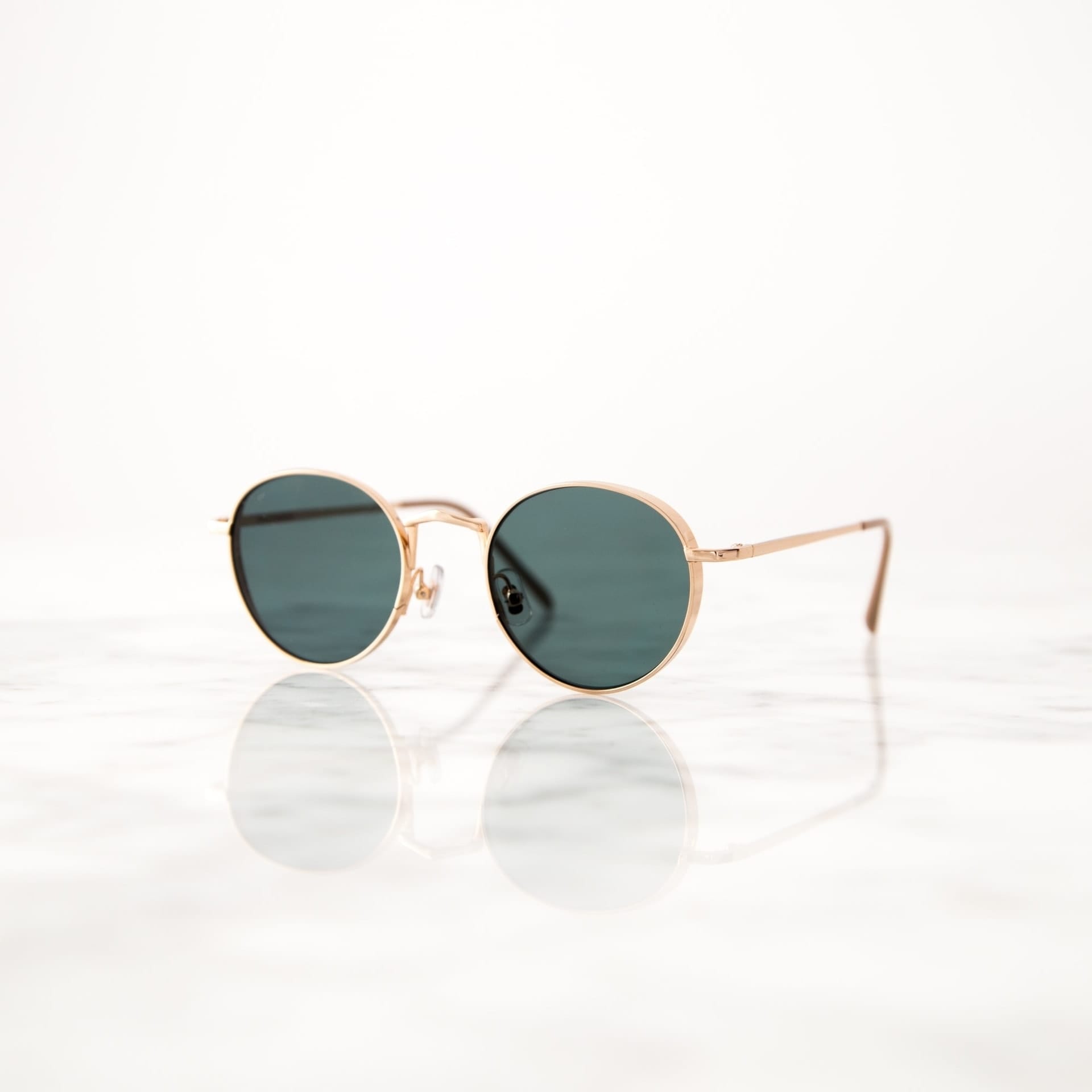 Gold frame sunglasses on reflective marble surface